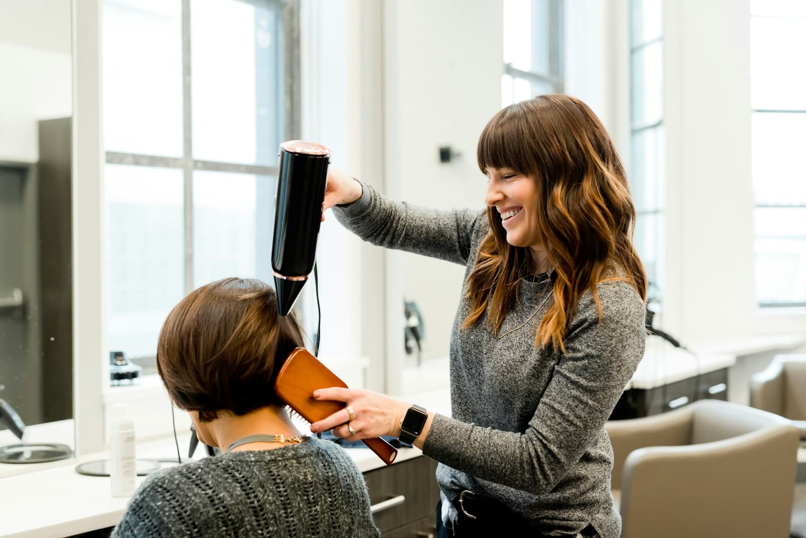 Coiffeuse souriante réalisant un brushing